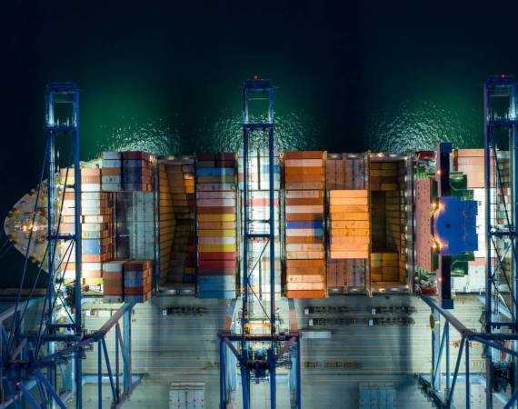 Aerial view At container terminal,crane lifts container from ship to truck to deliver goods to customer,Industrial business import and export Logistics and Supply Chain.
