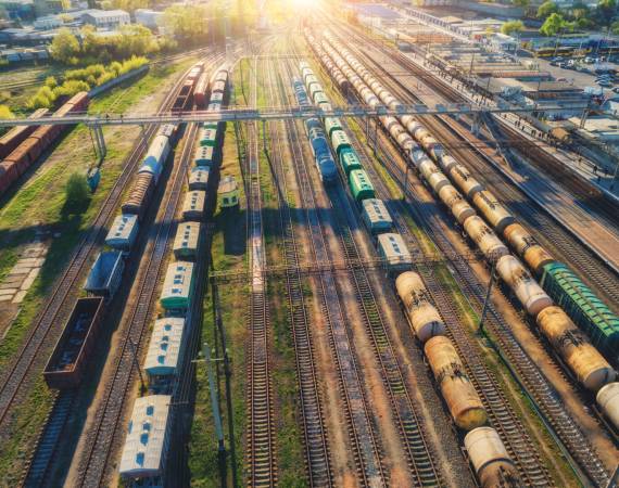 Cargo trains. Aerial view of colorful freight trains. Railway station. Wagons with goods on railroad. Heavy industry. Industrial scene with trains, railway platfform at sunset.Top view from drone